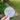 Round sticker with a snowman face design held in front of a blurred natural background