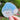 Hand holding a snowman sticker with  a blue santa hat trimmed with holly and berries on a blurred natural background