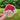 Sticker of a gingerbread face with a red  Santa hat held by a hand against a green outdoor background