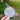 Round sticker with a snowman face design held in front of a blurred natural background